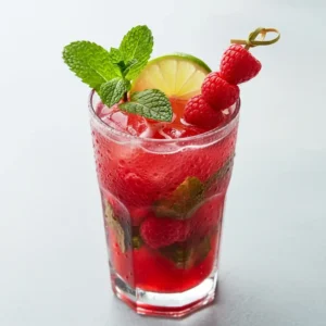 A fresh raspberry mojito in a tall glass, garnished with a mint sprig and fresh raspberries.