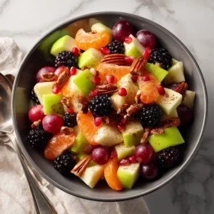 A close-up view of the autumn fruit salad in a serving bowl, highlighting the texture of the pomegranate seeds and crisp apples.