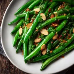 An overhead shot of Thanksgiving green beans being tossed in a skillet with a creamy garlic parmesan sauce and bits of bacon.