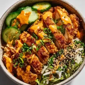 A close-up, top-down view of a Bang Bang Chicken Bowl, highlighting the crispy texture of the chicken and the creamy sheen of the sauce.