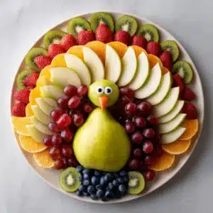 A close-up of a festive fruit platter for Thanksgiving, showing sliced pears, red grapes, and pomegranate seeds.