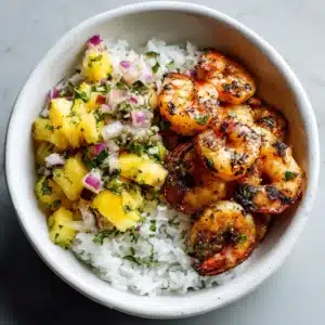 A close-up overhead view of a healthy shrimp bowl with rice, edamame, avocado, and carrots.