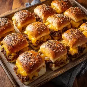 A tray of baked cheeseburger sliders on Hawaiian rolls, ready to be served for a party or family dinner.