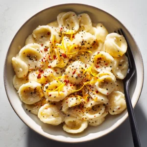 A high-angle shot of orecchiette pasta coated in a rich, creamy garlic lemon sauce, showcasing the dish's luscious texture.