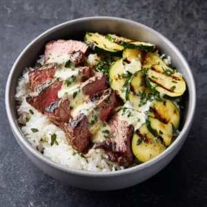 A healthy steak and rice bowl with fresh toppings in a minimalist grey bowl, ready to be eaten.