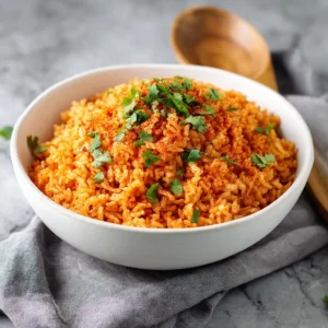 A close-up view of homemade Spanish rice in a white ceramic bowl, showcasing the fluffy texture of the individual grains.