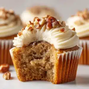 An extreme close-up shot of a banana pecan cupcake, highlighting the moist and fluffy texture of the cake and the crunchy pecan pieces within.