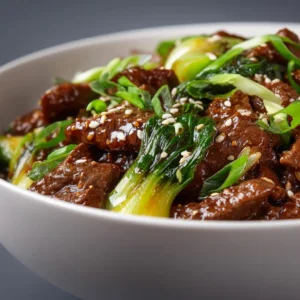 An extreme close-up shot of tender beef and bok choy stir fry, showing the glossy texture of the savory stir-fry sauce.