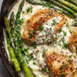 Close-up of freshly seared golden-brown chicken and blistered asparagus ingredients before making the cream sauce.