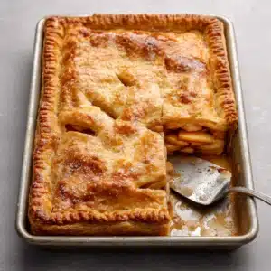 Close up of the steaming, juicy apple filling inside a golden-brown flaky Apple Slab Pie crust.