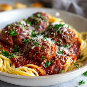 Rustic white shallow bowl filled with classic Italian Meatballs, rich tomato marinara, and fresh green parsley garnish.