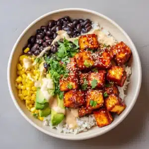 Ingredients for the vegan spicy baked tofu burrito bowl displayed neatly, showing cubed tofu, cornstarch, sriracha glaze, black beans, corn, and sliced avocado.