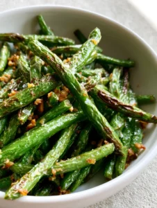 Smartphone photo showing vibrant green Air Fryer Green Beans with visible char marks and glistening oil.