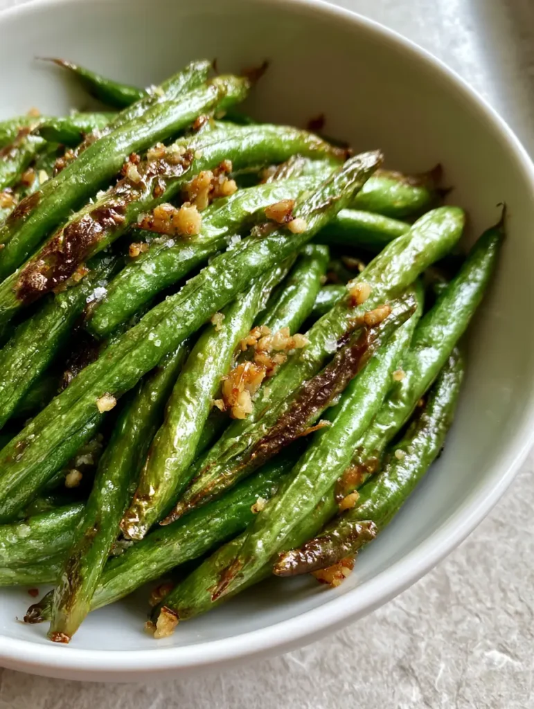 Close up of golden-brown crispy garlic bits on freshly cooked Air Fryer Green Beans.