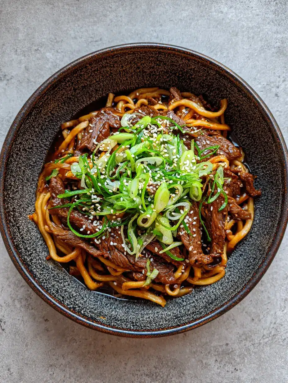 Sticky Beef Noodles featuring thick chewy wheat noodles and seared beef strips in a glossy dark brown sauce.