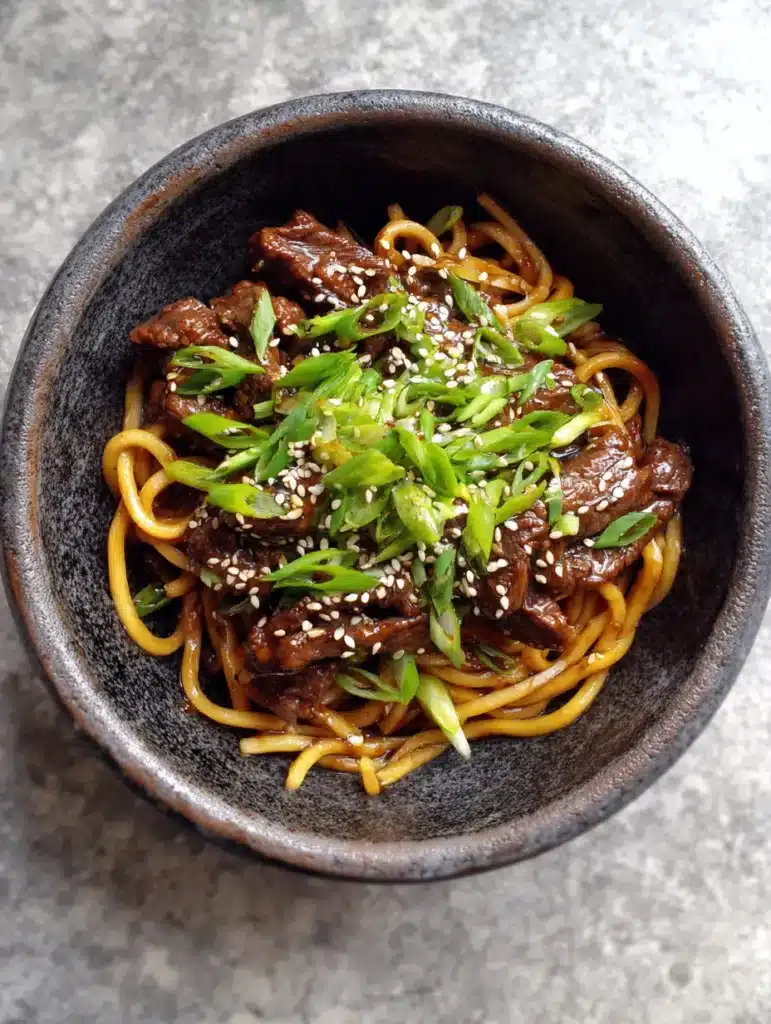 Handheld smartphone photo of beef noodles with seared edges and fresh scallion garnish.