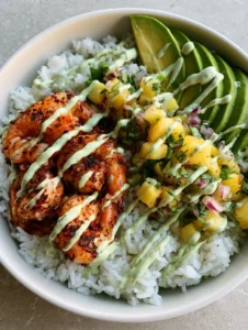 A shallow white ceramic bowl containing steamed jasmine rice, seared seasoned shrimp, and fresh pineapple salsa. (Shrimp Pineapple Rice Bowl)