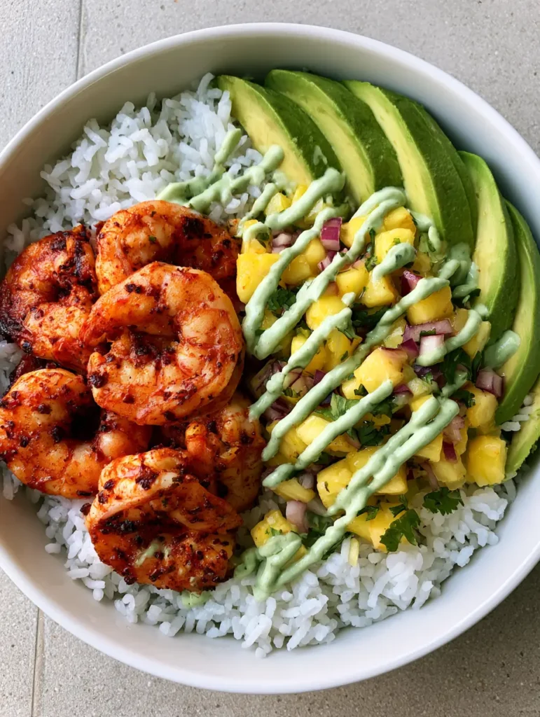 Shrimp Pineapple Rice Bowl with Chili-Seared Shrimp and Avocado Crema 1 Detailed shot of seared shrimp with chili flecks and vibrant green avocado crema zigzagged across the bowl.