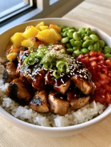 Top-down view of a Hawaiian Chicken Bowl featuring glossy amber glaze on chicken cubes and bright green edamame. (Hawaiian Chicken Bowl)
