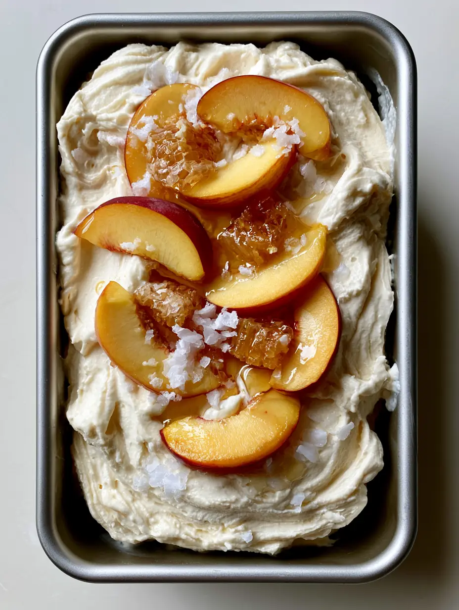 Overhead view of No Churn Peach Ice Cream featuring creamy ripples, orange peach slices with red skins, and golden honeycomb chunks.