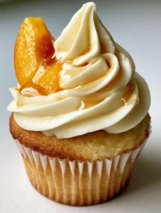 Close-up of Honey Peach Cupcakes showing the moist golden-brown sponge and smooth ivory frosting.