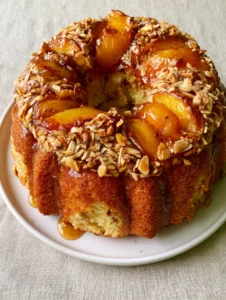 Close-up of the moist almond-flecked cake base and roasted peach wedges embedded in the golden-brown crust.