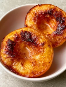 Close up photo of Air Fryer Peaches showing the golden-orange flesh and cinnamon dust finish on a stone background.