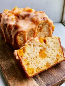 Close-up of a sliced loaf of Gluten-Free Peach Bread showing the moist, spongy interior and soft orange peach chunks. (Gluten-Free Peach Bread)